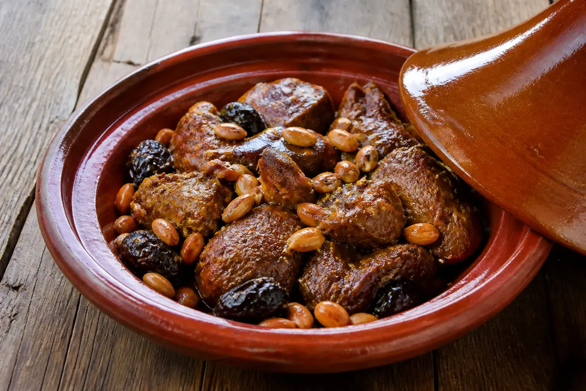 Plat traditionnel de tajine d'agneau aux pruneaux avec amandes dans un plat en terre cuite