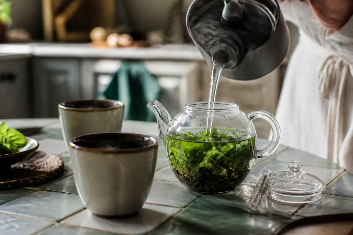 Préparation de thé à la menthe verte dans une théière en verre avec deux tasses.