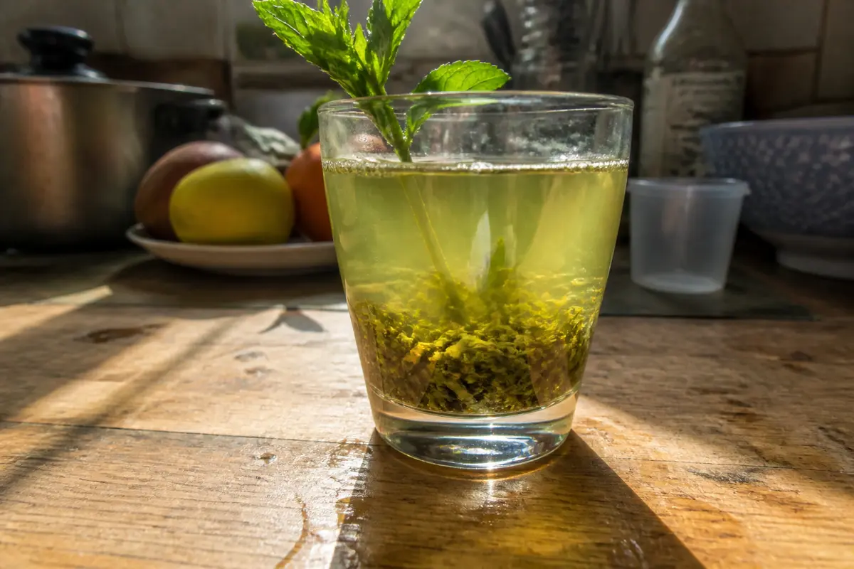 Verre de thé à la menthe fraîche, boisson traditionnelle de l'Oriental, sur table en bois